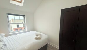 Ein Schlafzimmer mit einem Einzelbett, einem Fenster und einem dunklen Kleiderschrank.