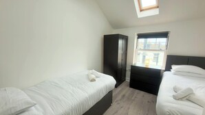 Een slaapkamer met twee bedden, een kledingkast, een raam en een dakraam.
