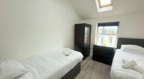 Ein Schlafzimmer mit zwei Betten, einem Kleiderschrank, einem Fenster und einem Dachfenster.