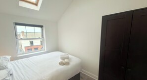 Ein Schlafzimmer mit einem Einzelbett, einem Fenster und einem dunklen Kleiderschrank.