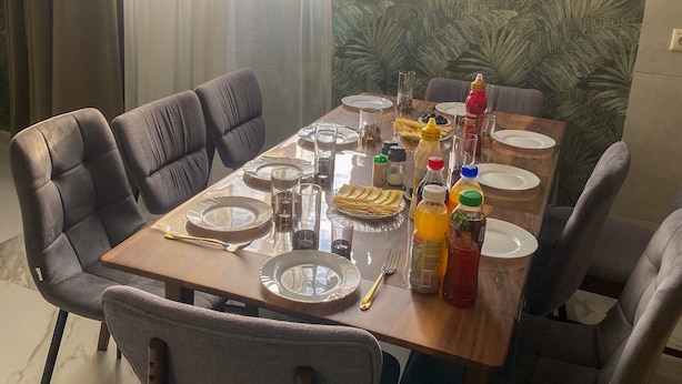 En matplats med ett bord dukat för fyra personer, stolar och ett fönster med gardiner.