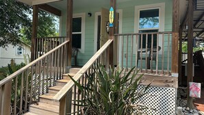 A wooden staircase leading to a porch with a white lattice fence, a wooden railing, and a number sign indicating the house number. - Joe's Place- A Hidden Gem by the Bay (Port St Joe)