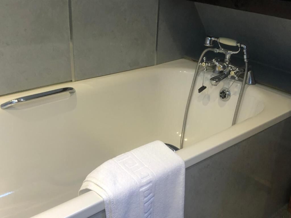 Una vasca da bagno con un rubinetto cromato e un porta asciugamani.