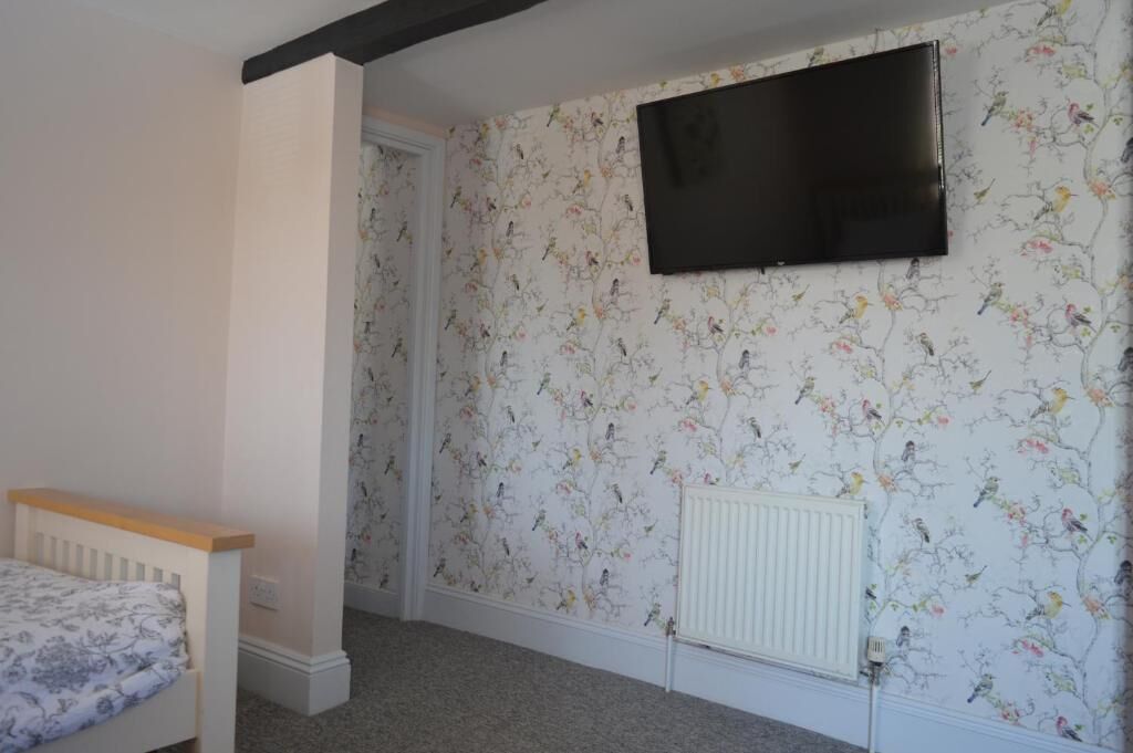 A bedroom with a bed, a radiator, and a TV mounted on the wall.