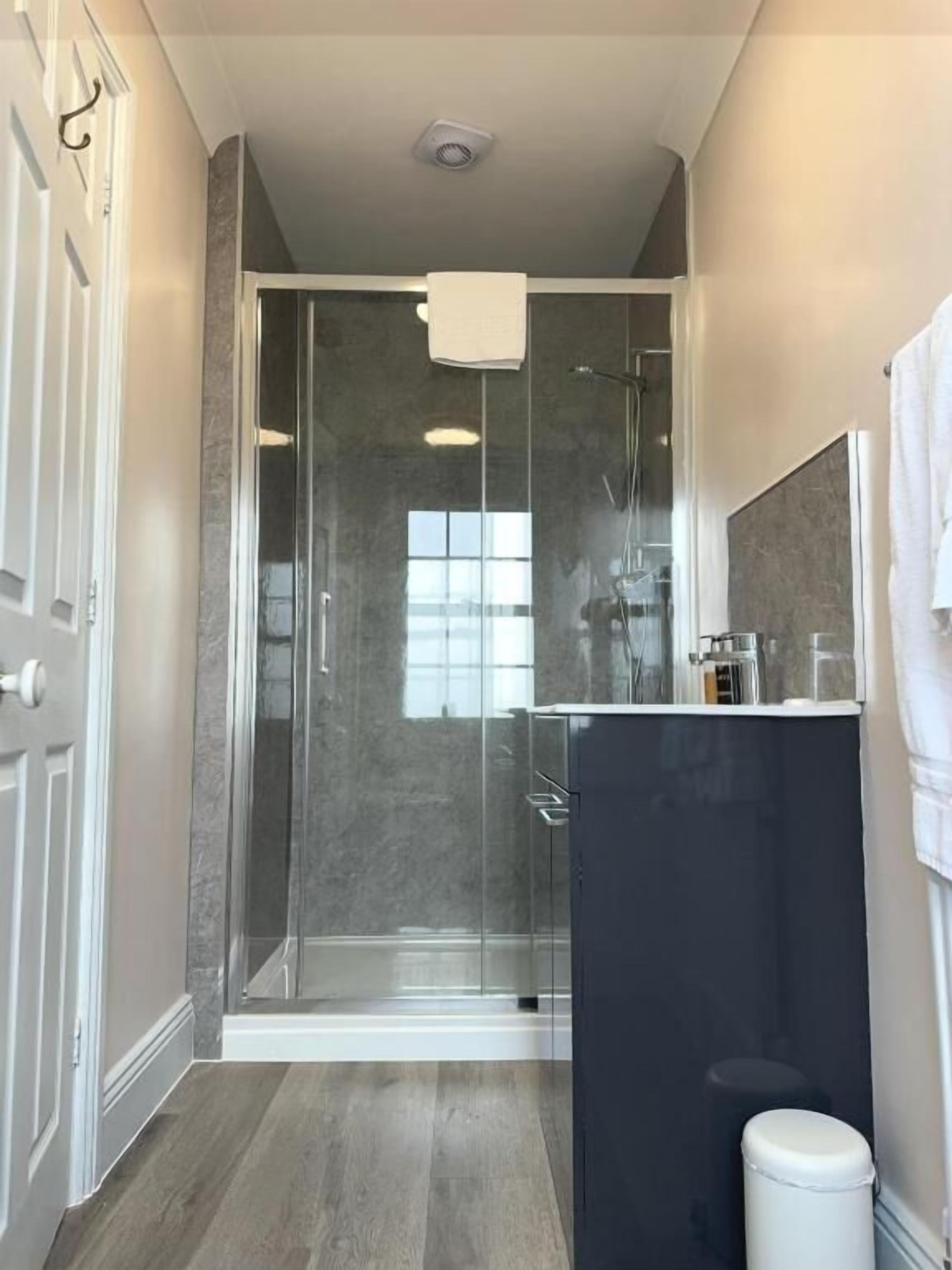 A modern bathroom with a glass shower enclosure, a dark vanity, and a white toilet.