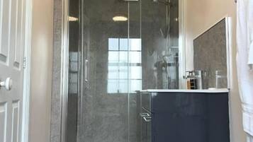 A modern bathroom with a glass shower enclosure, a dark vanity, and a white toilet.