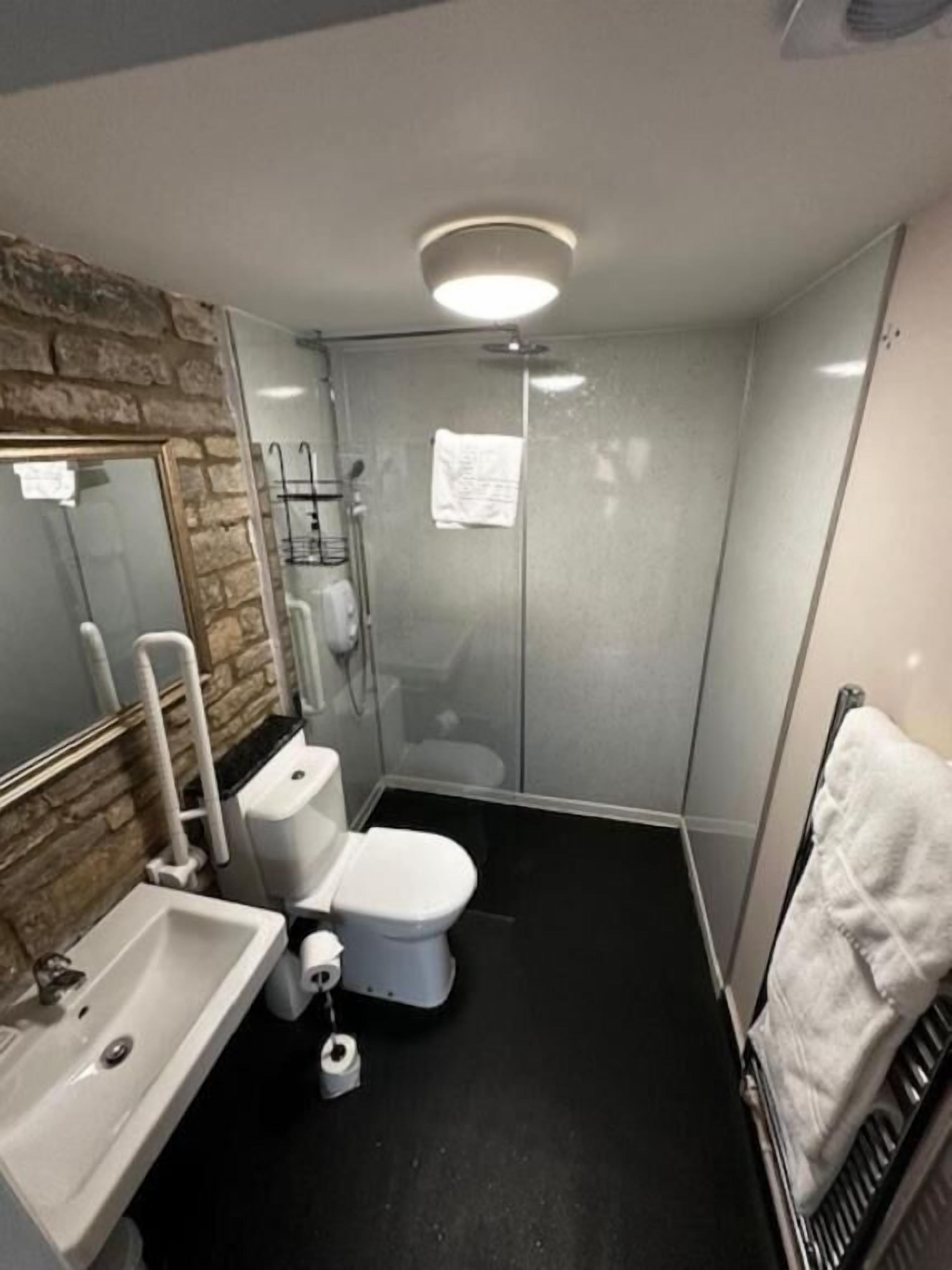 A modern bathroom with a glass shower enclosure, a white toilet, a sink, and a towel rack.