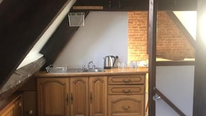 Een keuken met houten kastjes, een spoelbak, een waterkoker en een bakstenen muur.