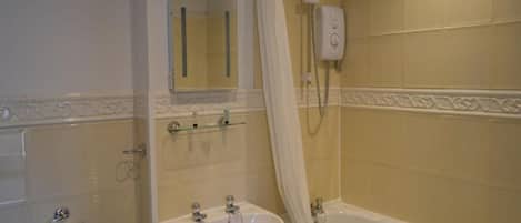 Un baño con bañera, lavamanos, espejo y ducha.