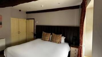 Un dormitorio con una cama grande, vigas de madera, un armario y una ventana.