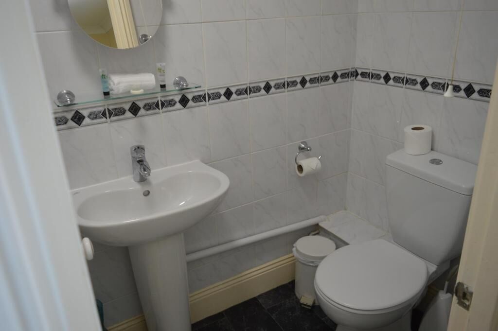 Une salle de bain avec un lavabo, des toilettes et un miroir.