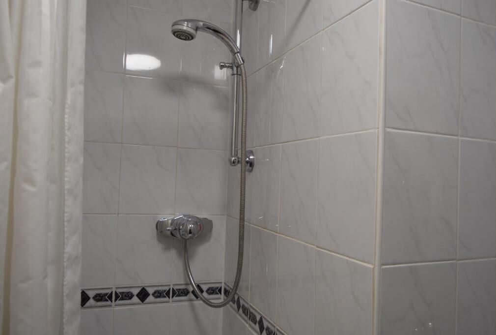 Een douche met een handdouche en een wandmengkraan.