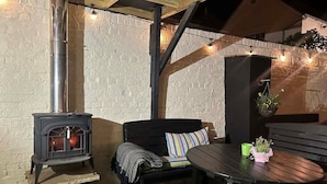 Een gezellig buitenverblijf met een houtkachel, een bank en een tafel.
