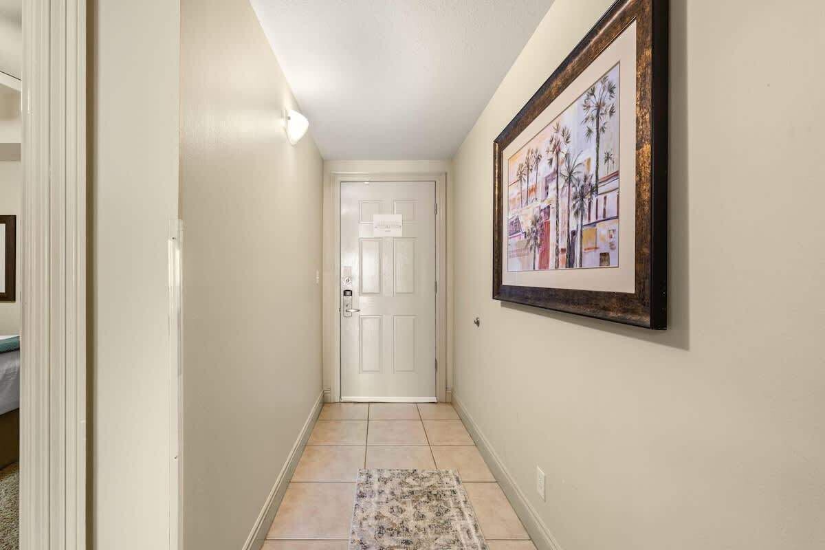 A hallway with a white door, a framed picture on the wall, and a patterned rug on the floor.