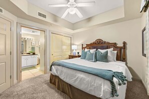 Une chambre avec un lit, un ventilateur de plafond et une vue sur la cuisine.
