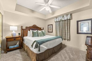 A bedroom with a bed, a nightstand, a lamp, a ceiling fan, and a window with curtains. - High Floor 1 bedroom with Gulf Views Plus Bunk Bed (Panama City Beach)