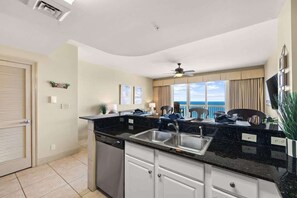 A modern kitchen with a black countertop, stainless steel sink, and white cabinets. - High Floor 1 bedroom with Gulf Views Plus Bunk Bed (Panama City Beach)