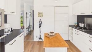 Una cocina moderna con armarios blancos, una mesa de madera y una lámpara colgante.