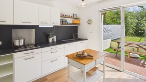 Una cocina moderna con armarios blancos, encimera negra y una mesa de madera con hogaza de pan.