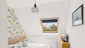 Un dormitorio con cama, ventana con vistas, radiador y escritorio con ordenador.