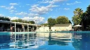 A clear blue pool with a covered area and a building in the background. - Poggio delle Ginestre Vacation Home in Torre a Mare, Bari—Pool, Parking, Sleeps 4 (Parco Scizzo-parchitello)