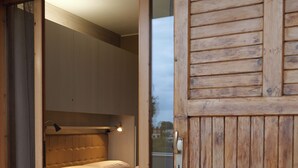A wooden door leading to a bedroom with a bed, a table with a colorful tablecloth, and a chair. - Poggio delle Ginestre Vacation Home in Torre a Mare, Bari—Pool, Parking, Sleeps 4 (Parco Scizzo-parchitello)