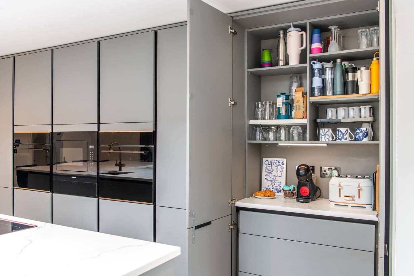 A modern kitchen with a built-in espresso machine, a coffee station, and various kitchenware.