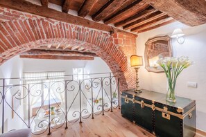 A room with a brick archway, a metal railing, a table with dishes, and a vintage suitcase. - Antica Tipografia in Lucca (Lucca)