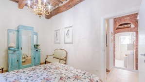 Un dormitorio con colcha estampada, un armario azul, una silla y un candelabro.