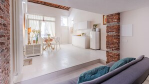 Un espacio moderno con cocina, comedor y un sofá con cojines estampados.