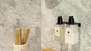 A bathroom with a marble backsplash, a soap dispenser, and a toothbrush holder. - Pana Unique Kolsay (Almaty)