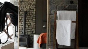 A room with a stone wall, a fireplace, a mirror, and a towel rack. - Pana Unique Kolsay (Almaty)