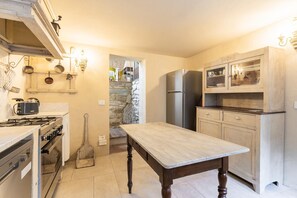A kitchen with a stove, oven, refrigerator, and wooden table.