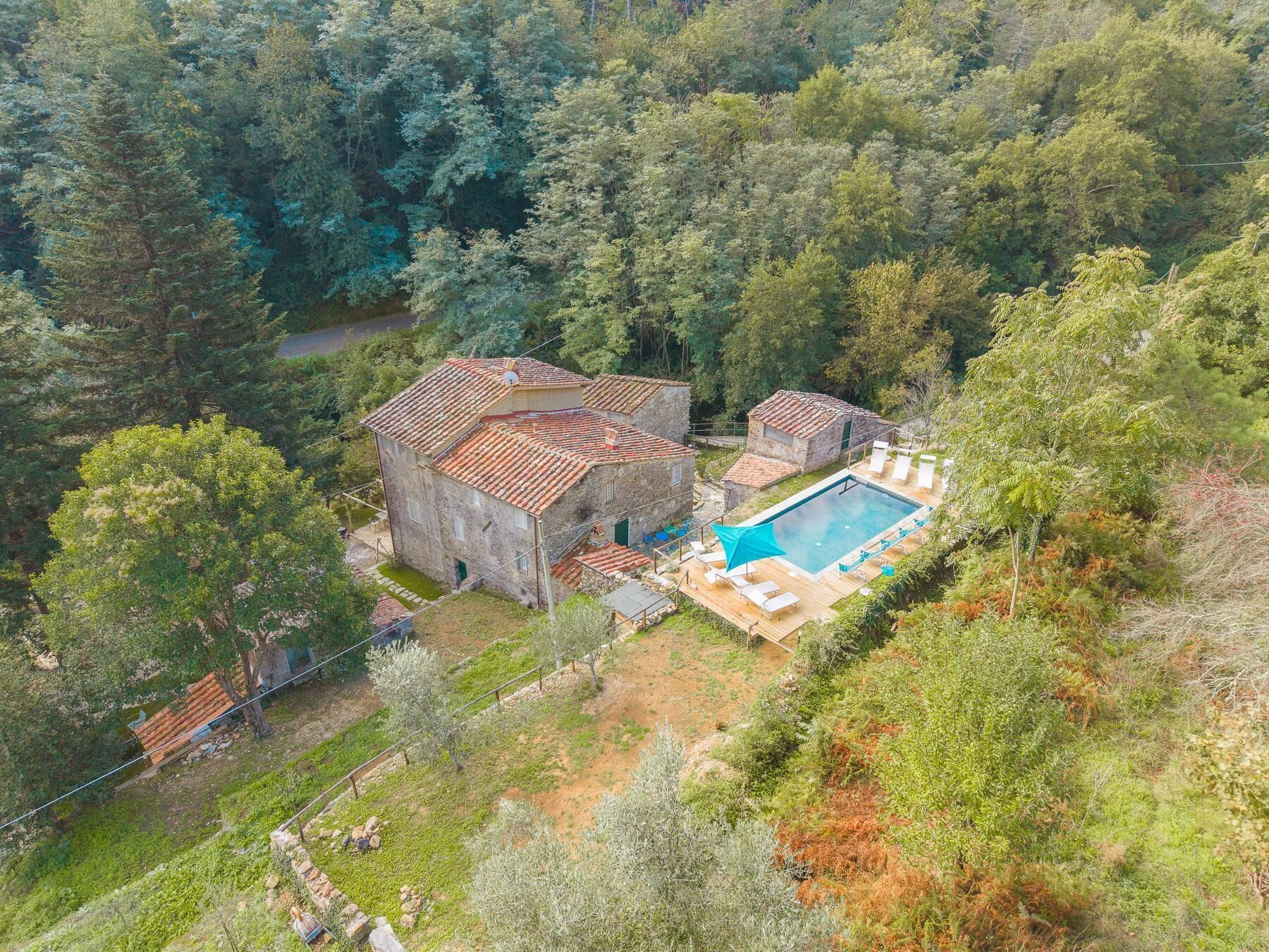 A stone building with a swimming pool surrounded by trees.