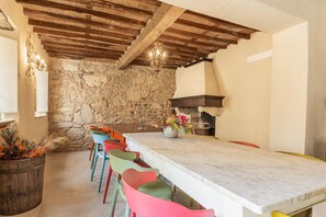 A stone wall, wooden beams, a marble table, colorful chairs, a candelabra, and a flower vase. - 7BR Tuscan Oasis with Pool_Borgo sulla Visona (Capannori)