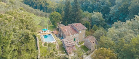 Una villa con piscina, rodeada de exuberante vegetación y colinas.