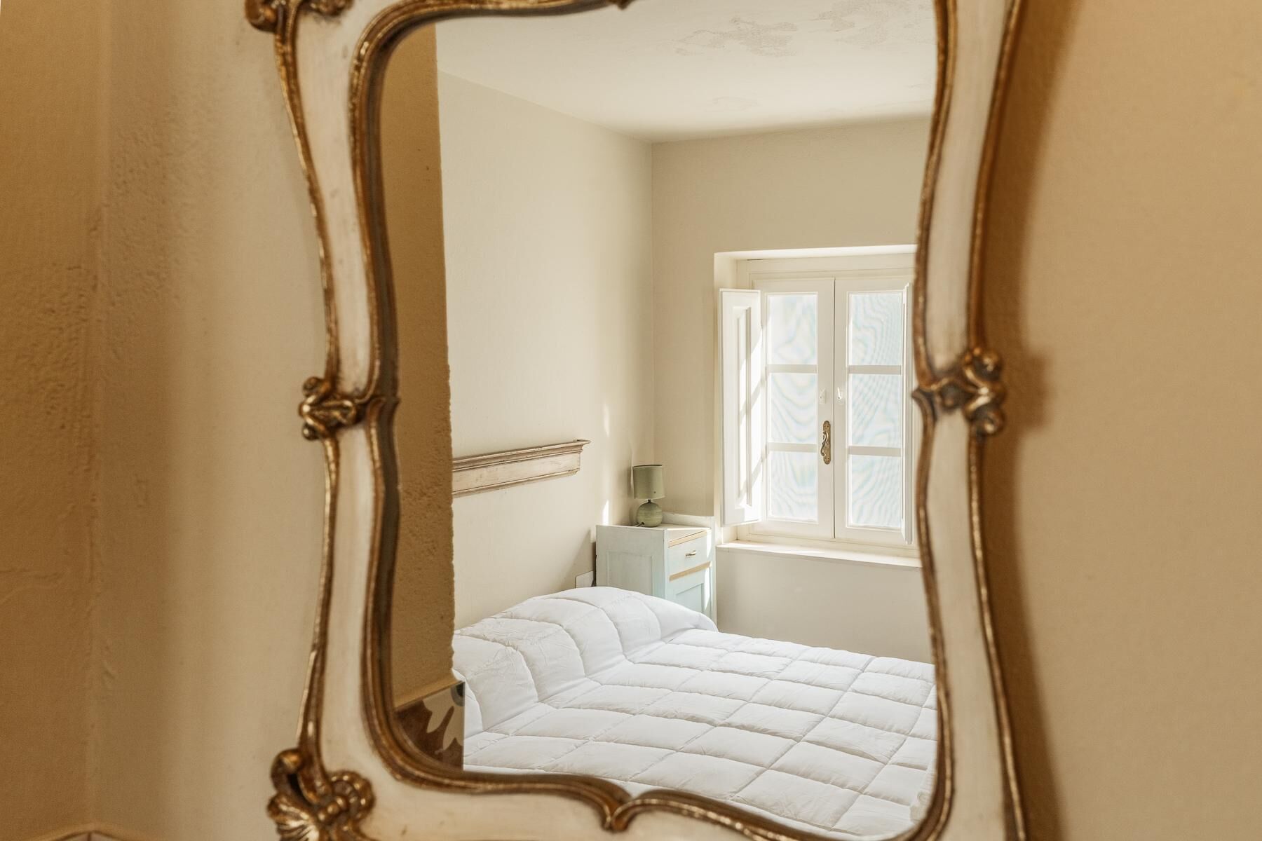 A bedroom with a bed, a nightstand, a lamp, and a window.