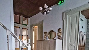 A staircase with a white railing, a wooden ceiling, and a green exit sign. - Kidalyo Hotel (Ayvalik)