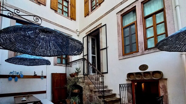A courtyard with a table and chairs, a staircase, and a door leading to an interior space. - Kidalyo Hotel (Ayvalik)