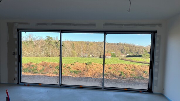 Ein Zimmer mit einer großen Schiebeglastür und Blick auf eine ländliche Landschaft.
