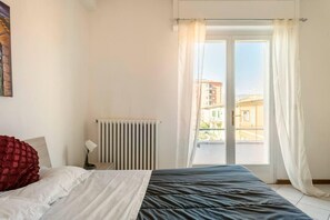 A bedroom with a bed, a radiator, and a window with curtains. - Three Bedroom Apartment (Montecatini Terme)