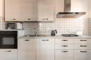 A modern kitchen with a built-in oven, microwave, gas stove, and stainless steel cabinets. - Three Bedroom Apartment (Montecatini Terme)