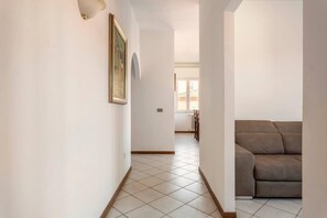 A hallway with a tiled floor leading to a living area with a sofa. - Three Bedroom Apartment (Montecatini Terme)
