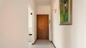 Un pasillo con una puerta de madera, un radiador y un cuadro en la pared.