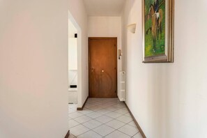 A hallway with a wooden door, a radiator, and a framed painting on the wall. - Three Bedroom Apartment (Montecatini Terme)