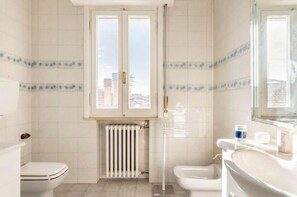 Een douche, een bidet, handdoeken, toiletpapier