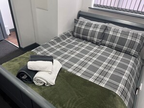 A neatly made bed with a plaid bedspread, a rolled-up towel, and a rolled-up mat. - 4 ensuite bedroom home with parking in Broomhill 5 mins to centre & hospital (Sheffield)
