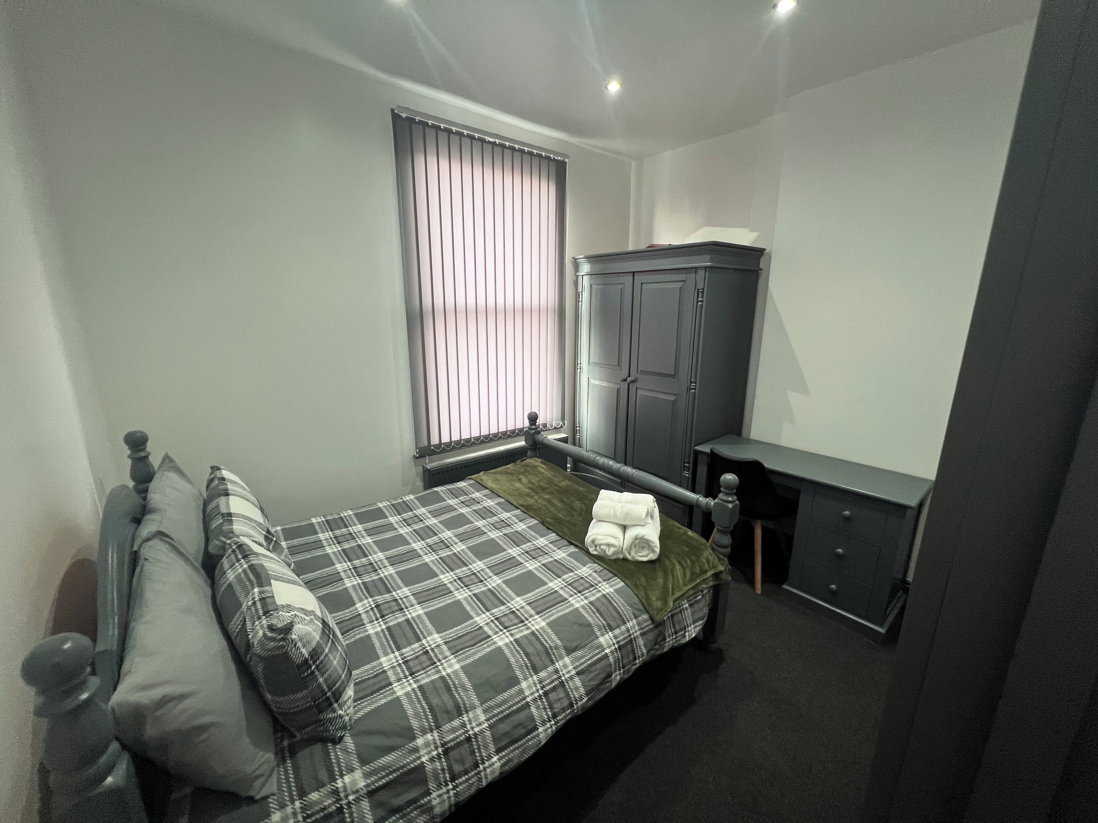 Une petite chambre à coucher, bien rangée, avec un lit, une armoire et un bureau.