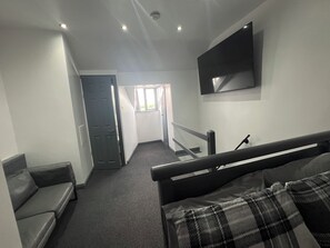 A narrow hallway with a sofa, a bed, and a TV mounted on the wall. - 4 ensuite bedroom home with parking in Broomhill 5 mins to centre & hospital (Sheffield)