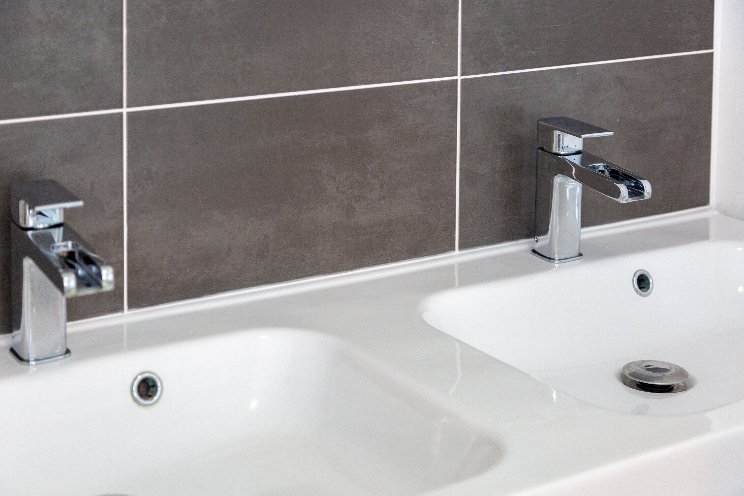 A bathroom with two sinks and chrome faucets.